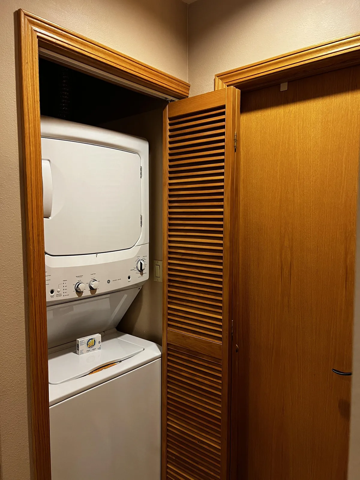 A laundry room with a modern washing machine and dryer, accented by golden wood trim and a functional yet inviting layout. The space is clean and practical, underscoring guest convenience.