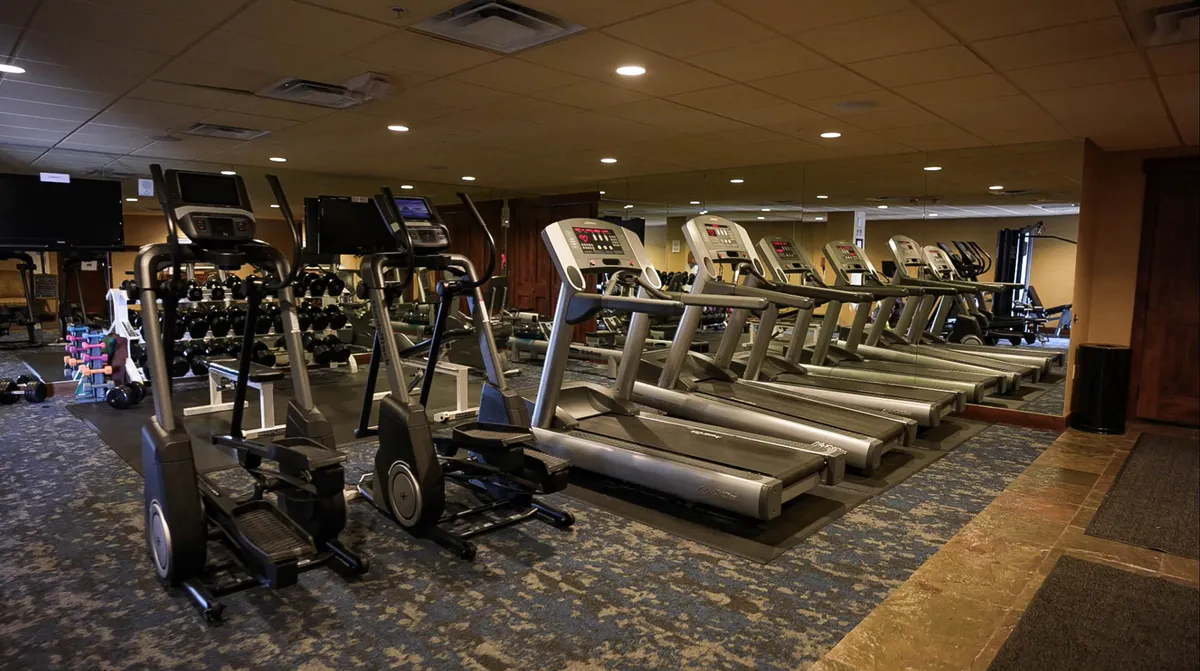 A well-equipped fitness center featuring treadmills, elliptical machines, and a dumbbell rack. The space is bright and modern, inviting guests to work out or join a group fitness class.